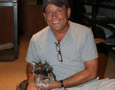 Man in casual clothing and cap sitting on the floor with a dog